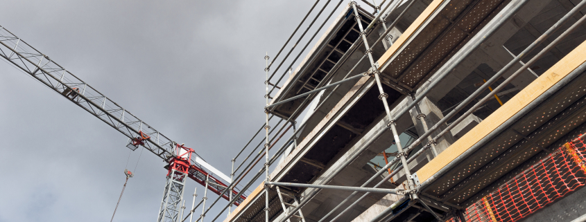 Building construction site with crane and scaffolds - Sorglos Bauen GmbH