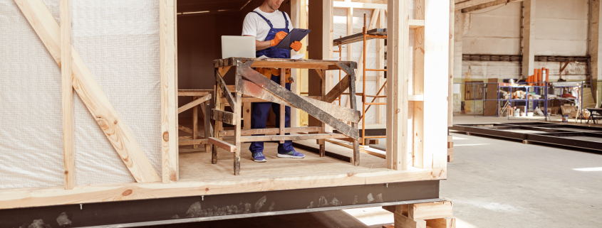 Male builder writing on clipboard at construction site - Sorglos Bauen GmbH