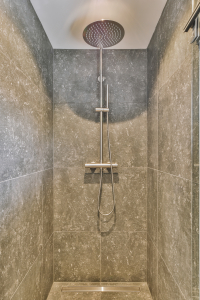 Open shower in gray tiled room - Sorglos Bauen GmbH