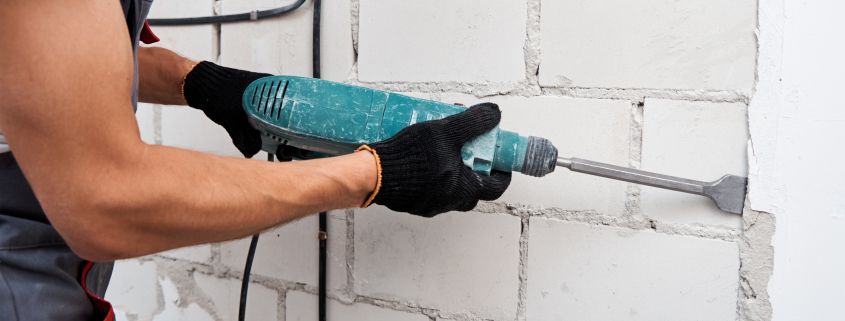 Man with demolition hammer remove stucco from wall. Renovation concept - Sorglos Bauen GmbH