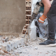 Unrecognizable man using a jackhammer to drill into wall. - Sorglos Bauen GmbH