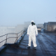 Worker scientist wearing protective coverall and gas mask doing ecological tests on the roof - Sorglos Bauen GmbH