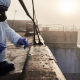 Worker scientist wearing protective coverall and gas mask doing ecological tests on the roof - Sorglos Bauen GmbH